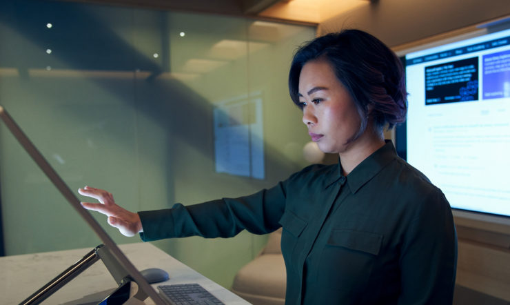 nainen, joka seisoo tietokoneen näytön edessä