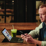 een man zit aan een tafel en gebruikt een laptop