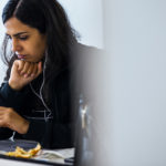 a person sitting at a table using a laptop computer