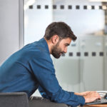 A man sitting at a table using a laptop