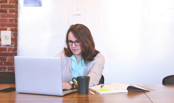 een vrouw zit aan een tafel en gebruikt een laptop