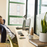 a person sitting at a desk in front of a window