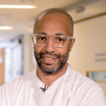 A smiling man wearing glasses looking at the camera