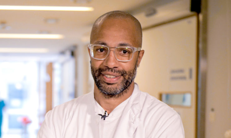 A smiling man wearing glasses looking at the camera