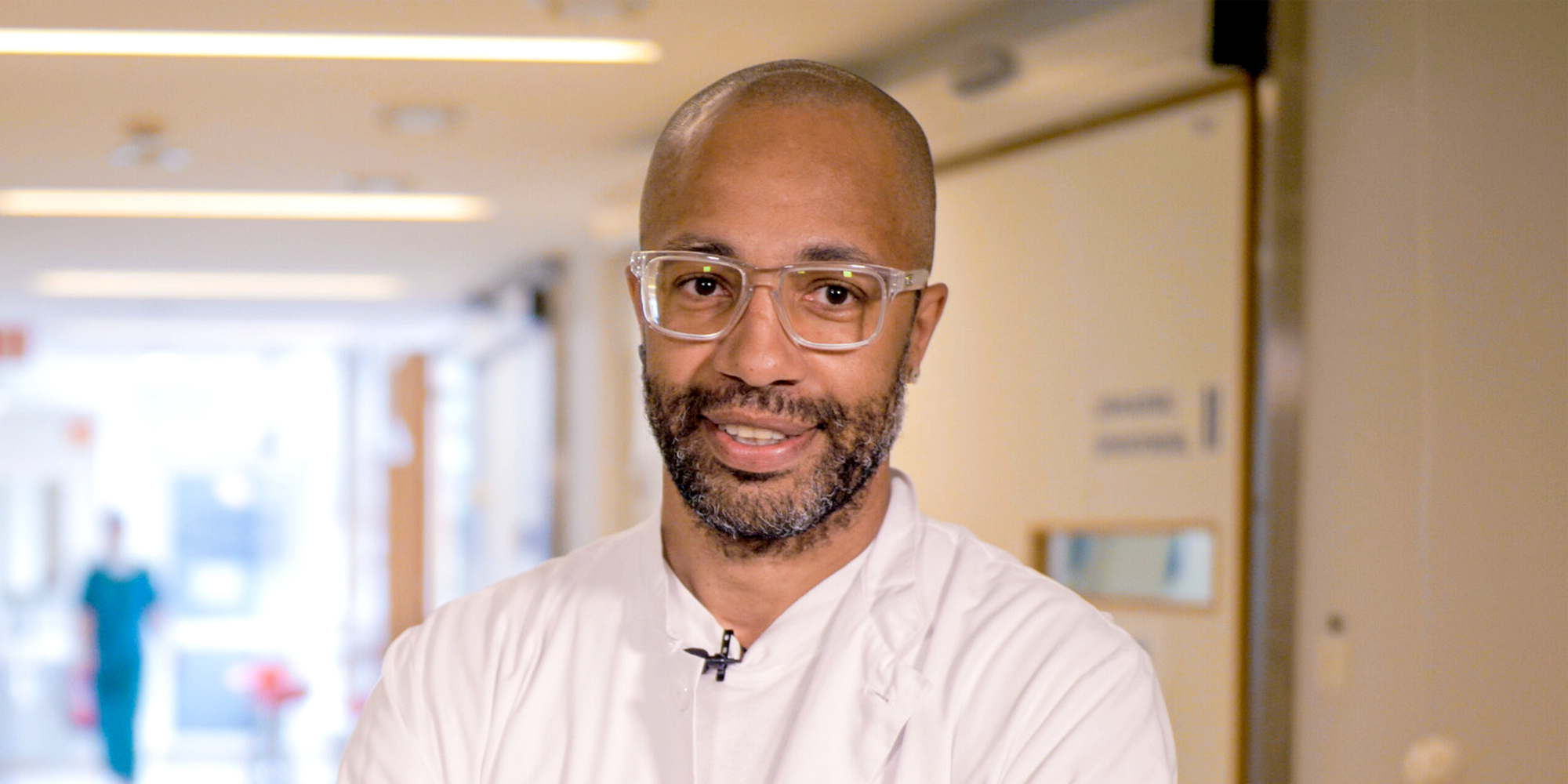 A smiling man wearing glasses looking at the camera