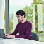 a person sitting at a table using a laptop computer