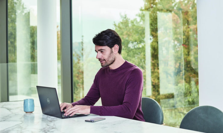 a person sitting at a table using a laptop computer