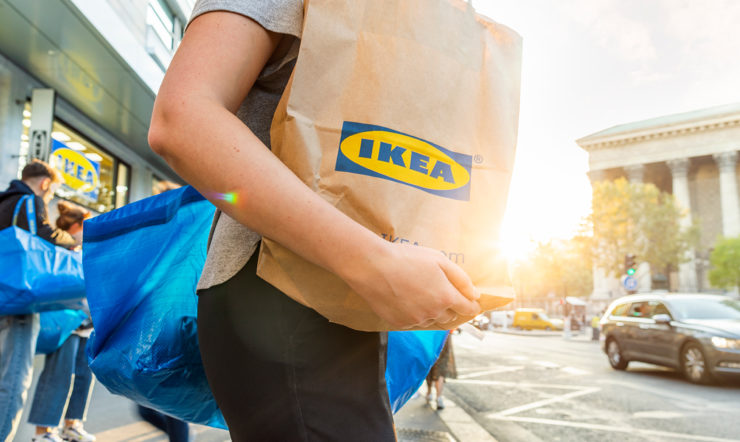 a person walking down a street with an Ikea bag