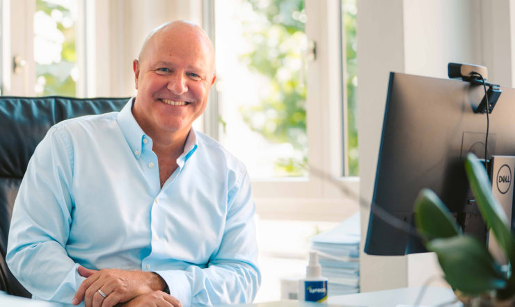 A man sitting down and smiling at the camera