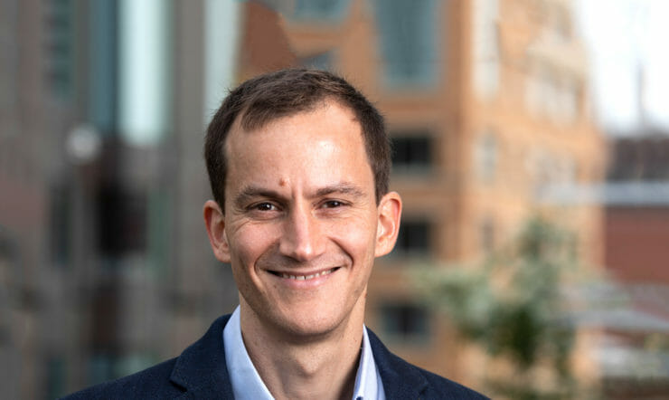 a man wearing a suit and tie smiling at the camera