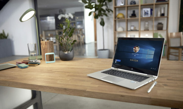 et skrivebord med en bærbar datamaskin som sitter på toppen av et trebord