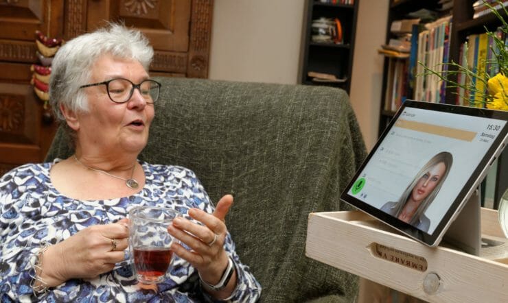 een persoon die aan een lijst zit die laptop gebruikt