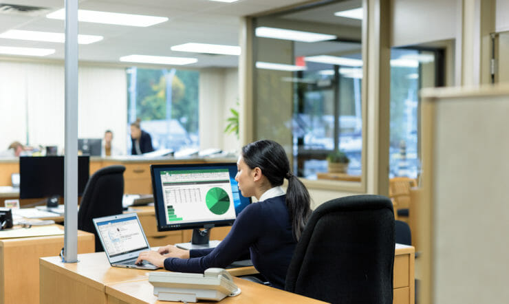 een persoon die aan een lijst zit die laptop gebruikt