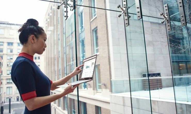 eine Frau, die in einem Gebäude steht und einen Laptop in der Hand hat