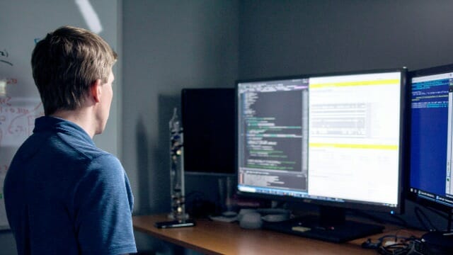 um homem sentado em uma mesa com um monitor de computador