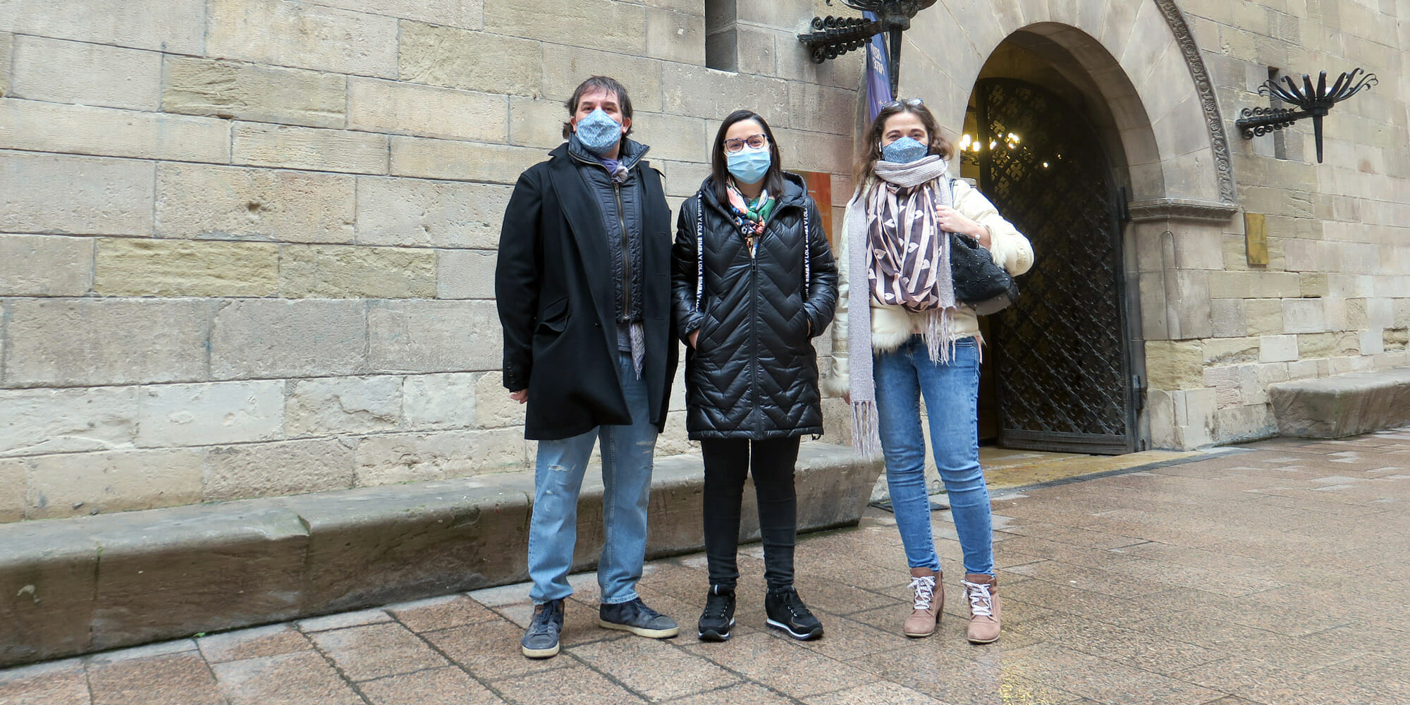 a man and two women standing in front of a brick building