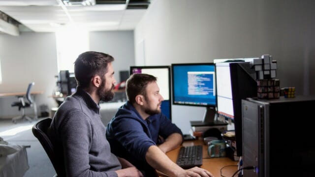 Dois homens a trabalhar à frente de um computador.