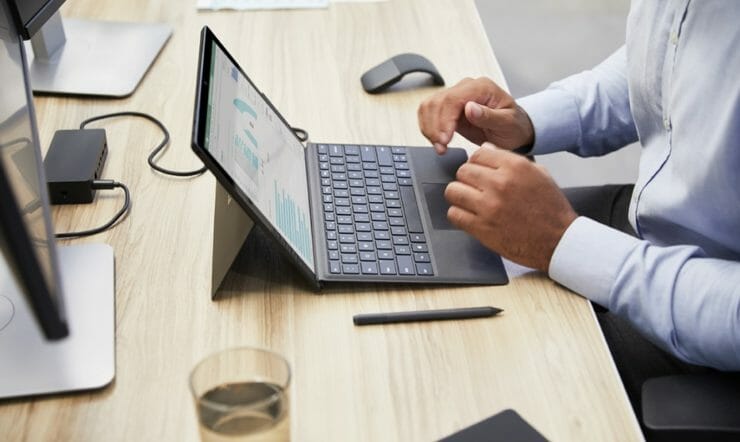 een mens die een laptopcomputer gebruikt die bovenop een houten lijst zit