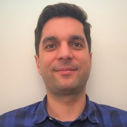 en mann iført en blå skjorte og smiler på kameraet