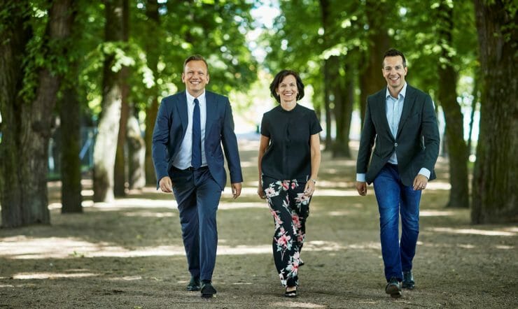 en gruppe mennesker som står ved siden av en mann i dress og slips