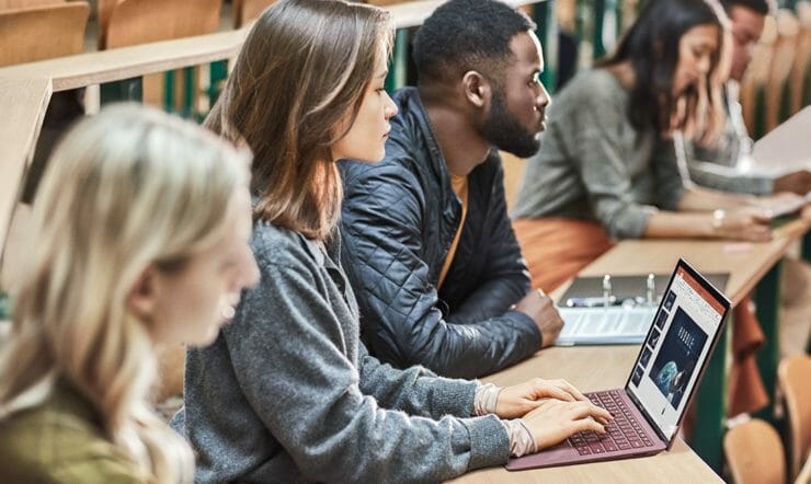 students behind desk with laptop