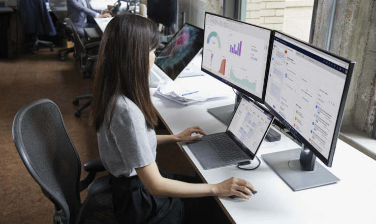 woman in front of two screens and a laptop