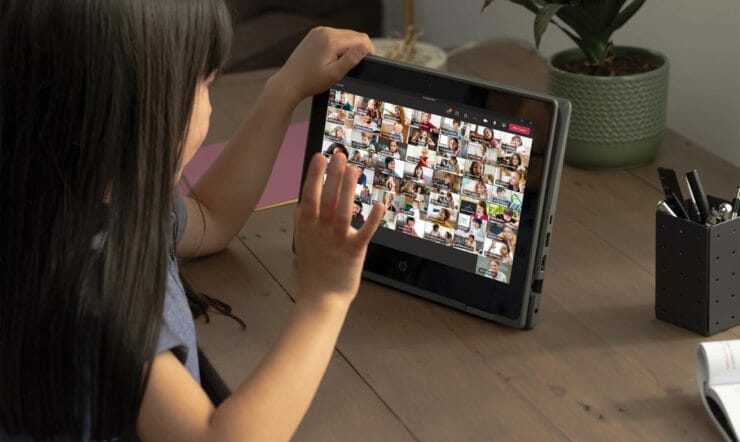 Mädchen tippt auf den Touchscreen ihres Gerätes während ihres Teams Meetings