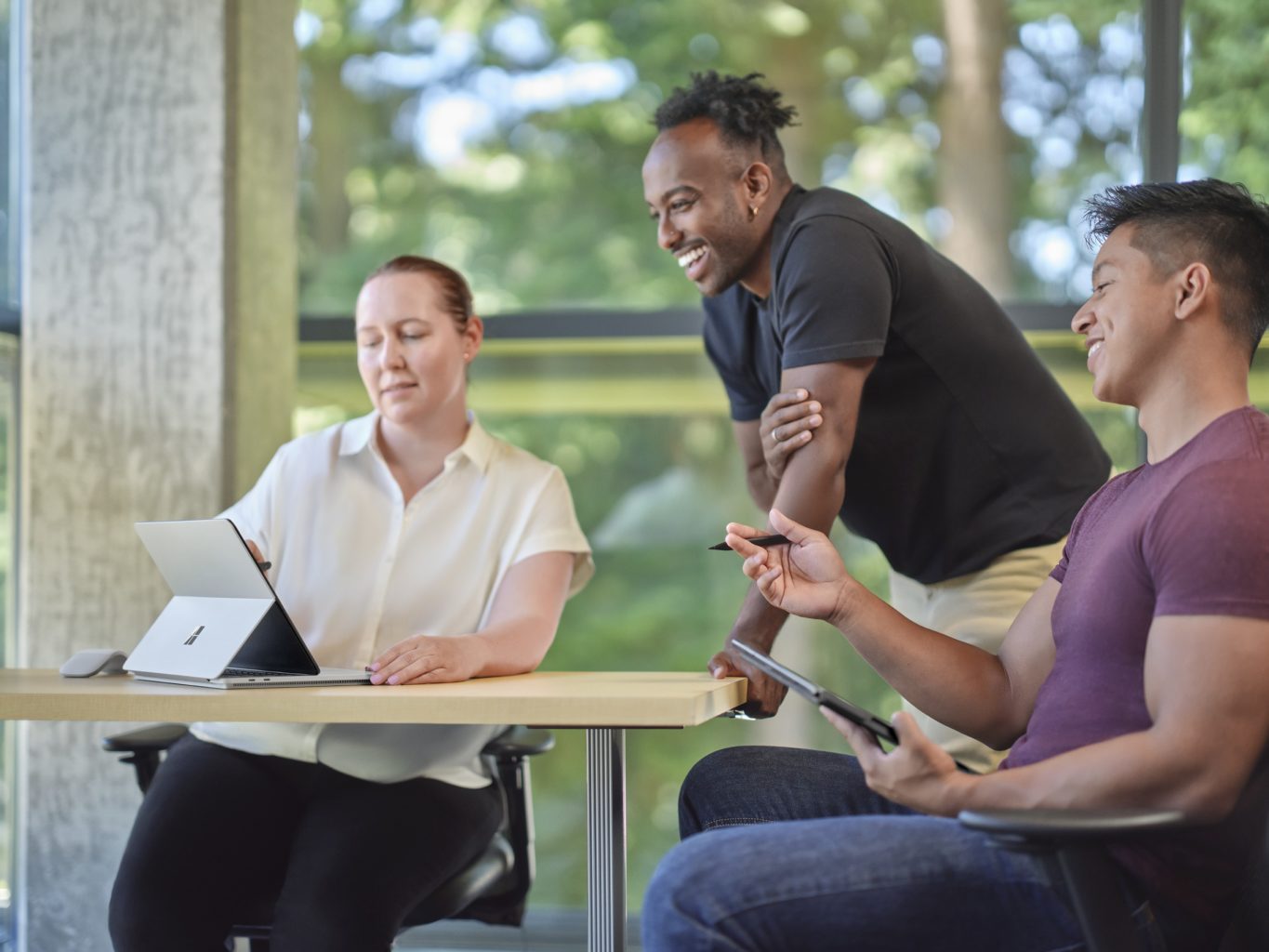 Two students and a teacher are looking at a Surface Laptop Studio.