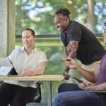 Two students and a teacher are looking at a Surface Laptop Studio.