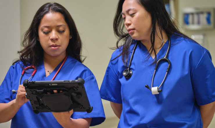 One nurse is holding a Surface Go 3 and Surface Pen while sharing the screen with another nurse.