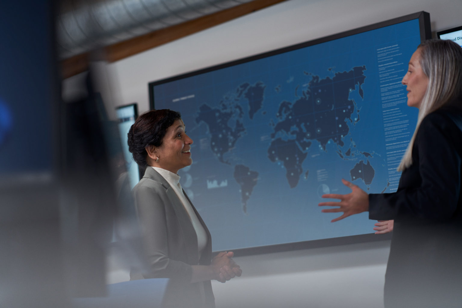 To ansatte står foran en skjerm som viser et verdenskart med markerte punkter