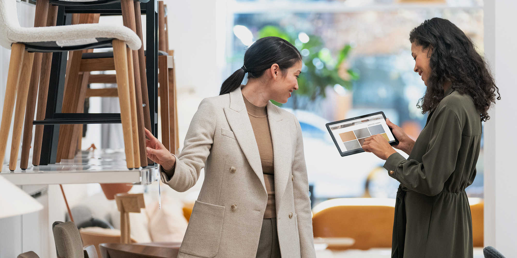 Two women in a furniture shop looking at color tones on a tablet