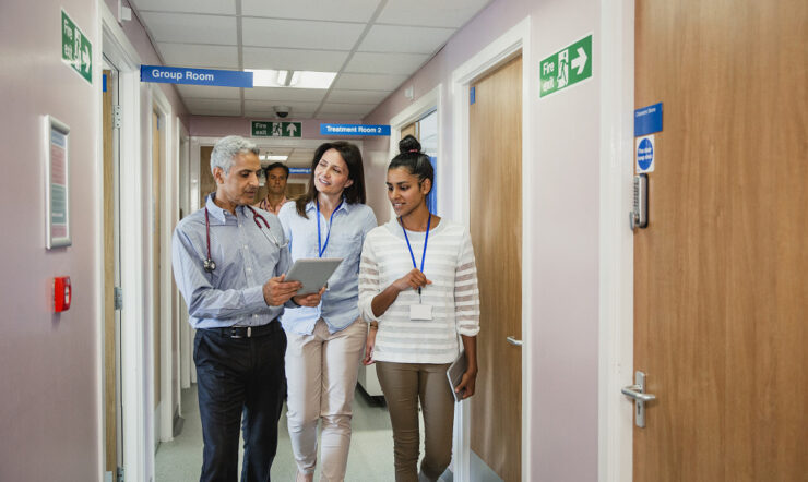Two women and one man in a hospital looking at a tablet