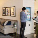 man and woman in a store looking at a large touch screen