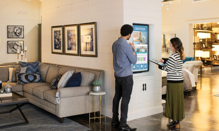 man and woman in a store looking at a large touch screen