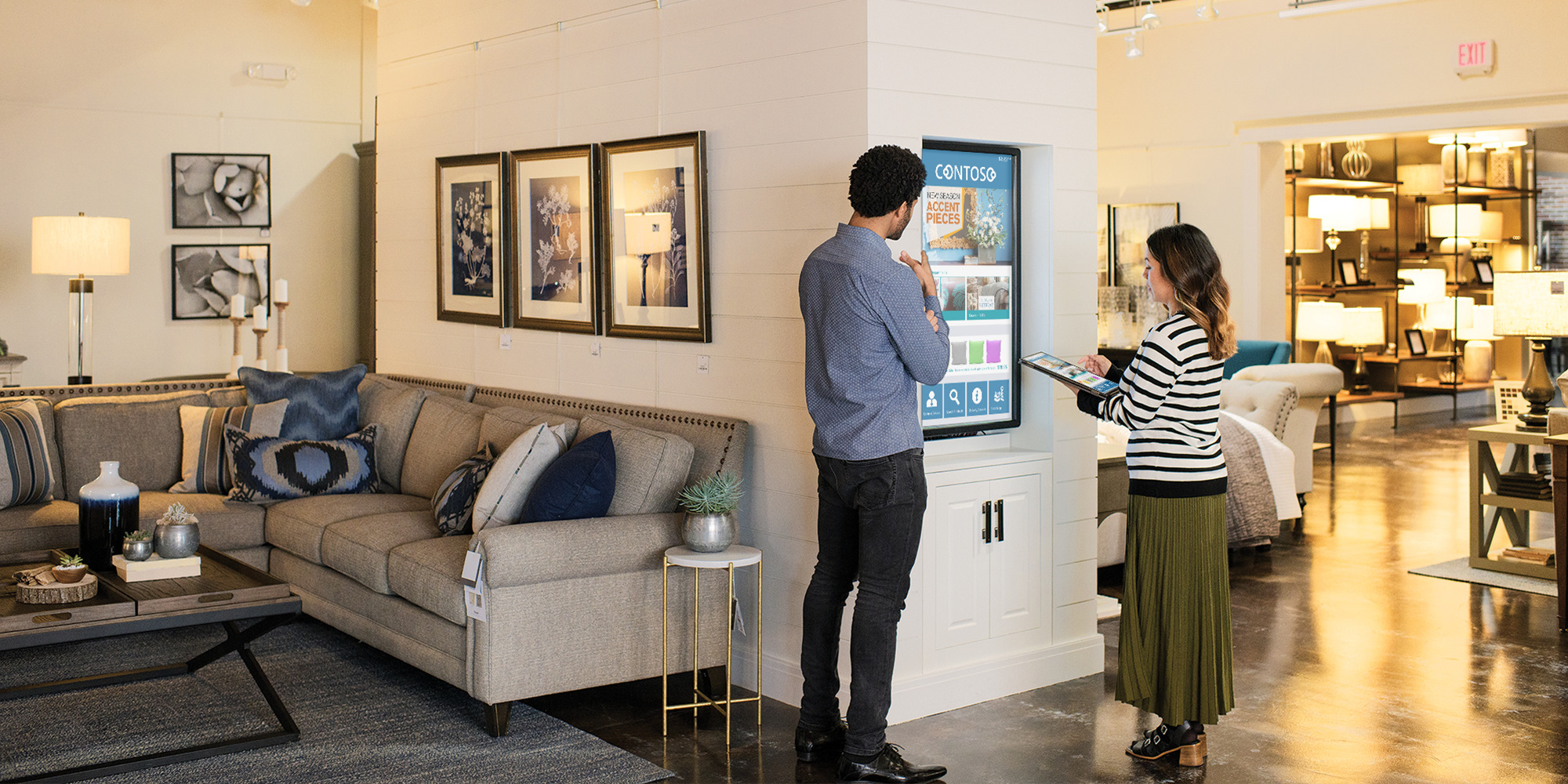 man and woman in a store looking at a large touch screen