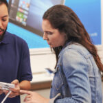 Male store associate helping female customer in tech shop