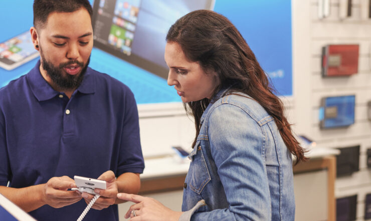 Male store associate helping female customer in tech shop