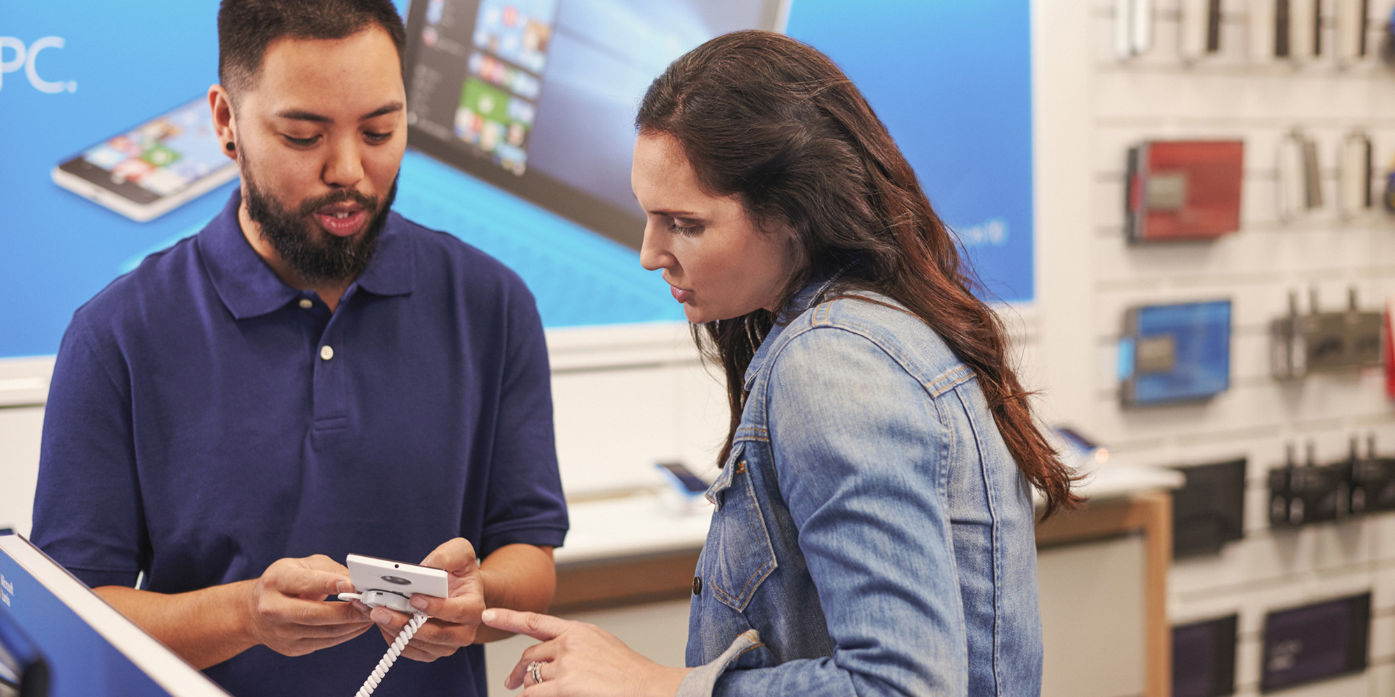 Male store associate helping female customer in tech shop