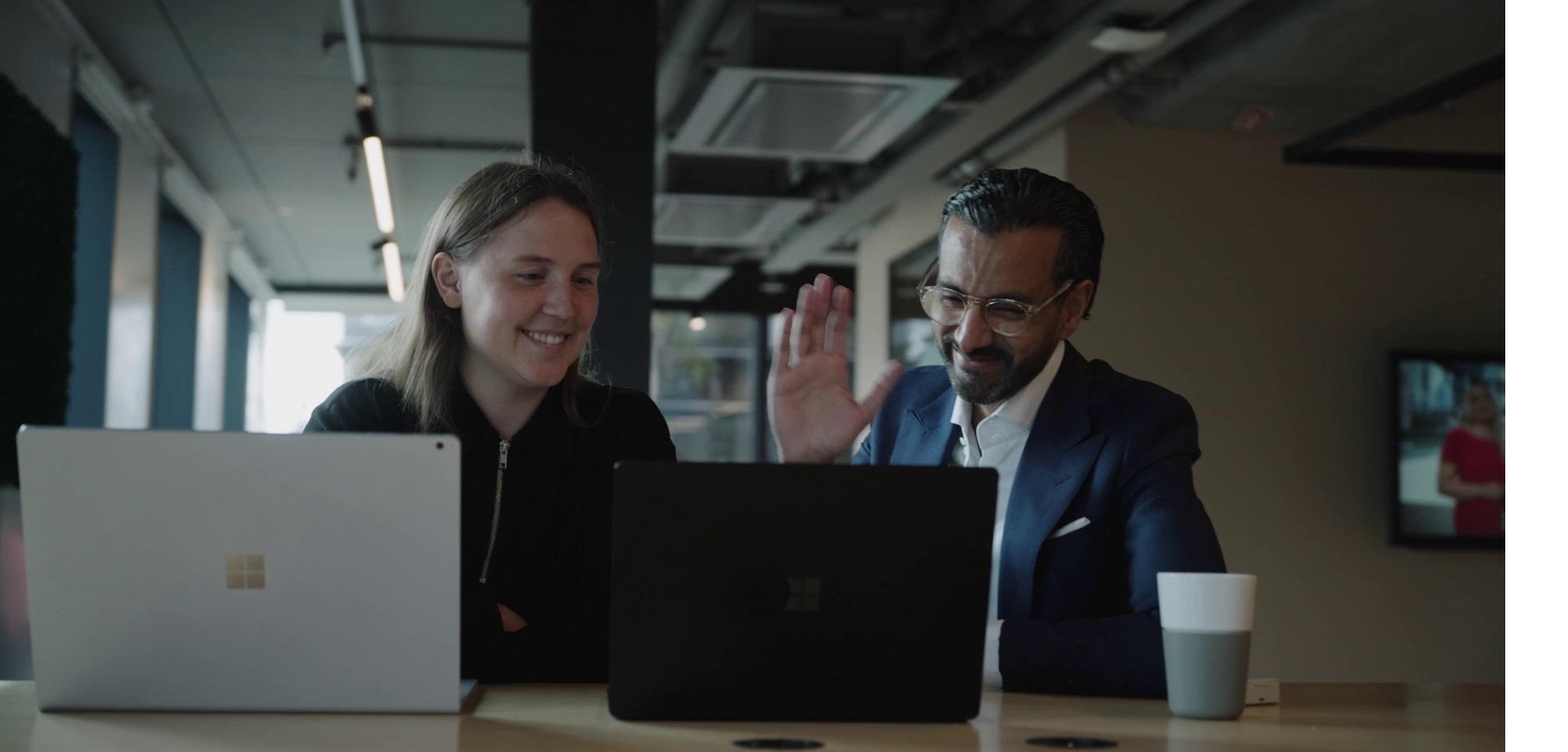 Kvinna och man framför varsin laptop har ett möte med andra via Teams Rum