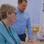 A man and a woman looking at a computer with info graphics