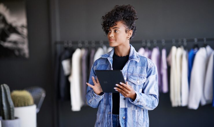 Azure solution in retail store. Empowered retails store manager in focus work viewing real-time data powered by Azure. Persona: Amber Rodriguez; retail store manager; Azure; retail; scale; global; fashion; working in Azure; powered by Azure; building on Azure; inventory; planning; scheduling; IoT; internet of things; real time data; work anywhere; positive; confident smile; looking up; satisfaction; satisfied; female; woman; holding Surface tablet; boutique; Azure technology innovation; Azure analytics; intelligent solutions; Azure intelligent apps; alpha channel; alphachannel; mask; clipping path; transparent background; isolated; knockout; outlined; outline