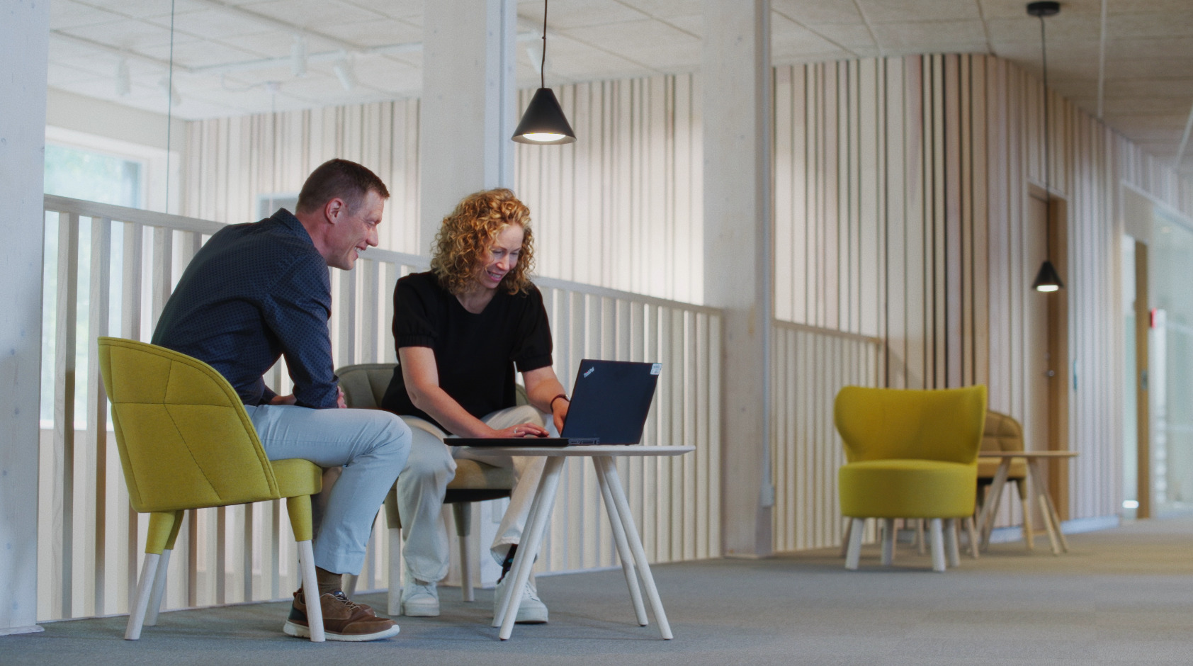 A man and a woman in an office looking at a laptop screen