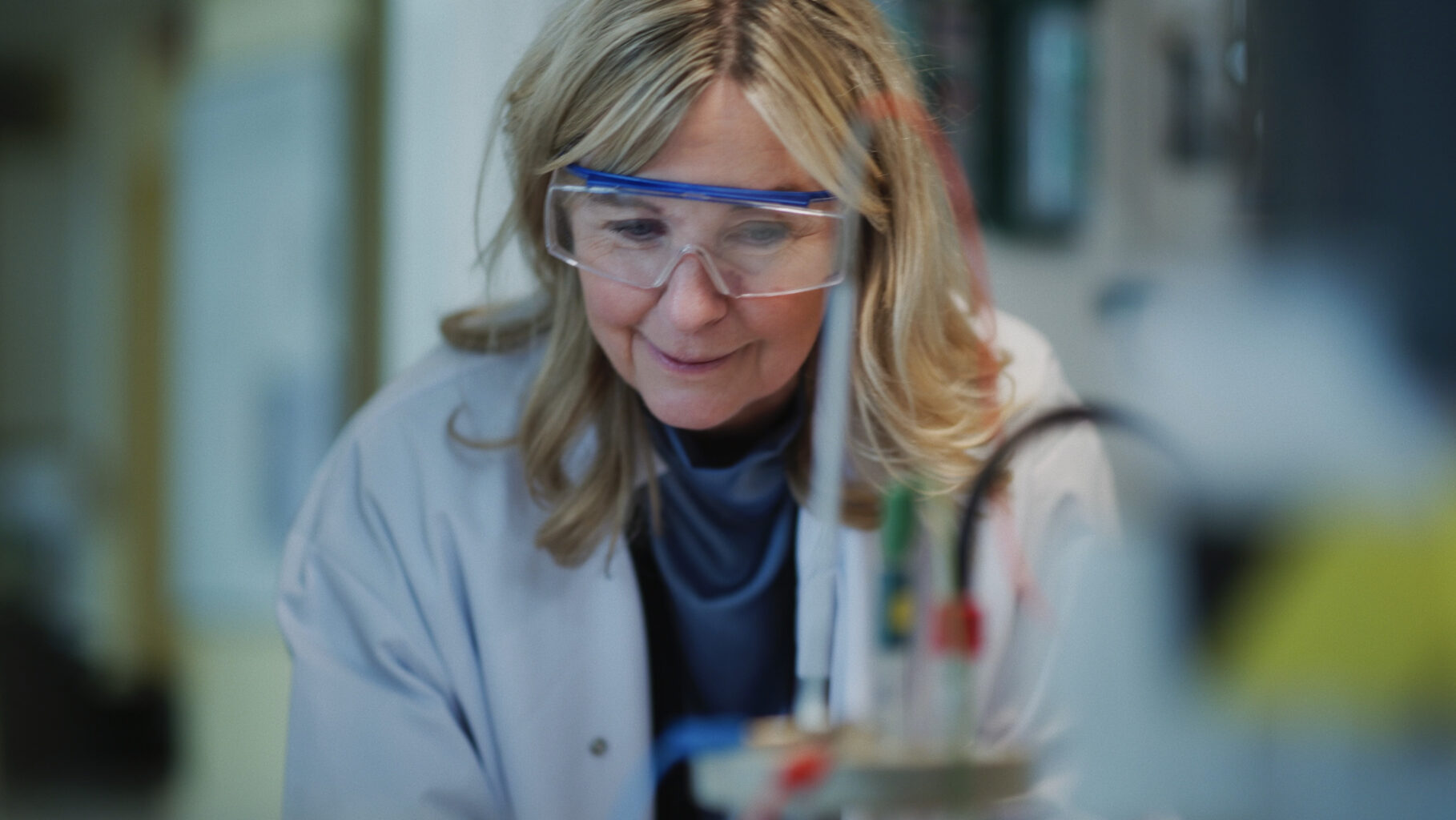 A woman in a lab coat and protective glasses