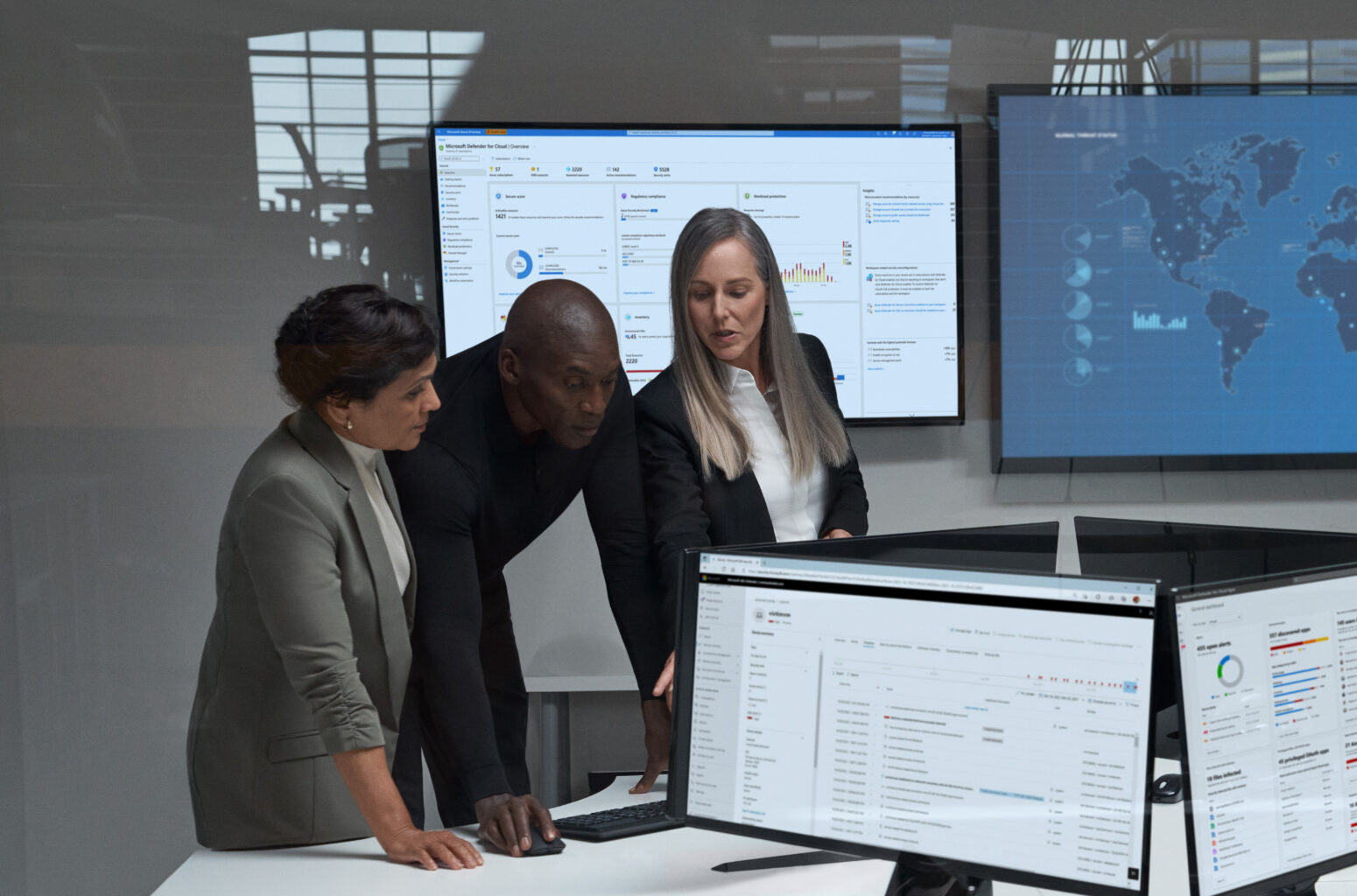 CISO (chief information security officer) collaborating with practitioners in a security operations center. Keywords: Security; operations; two women; man; wall map; soc; war room; Microsoft Defender; threat hunting