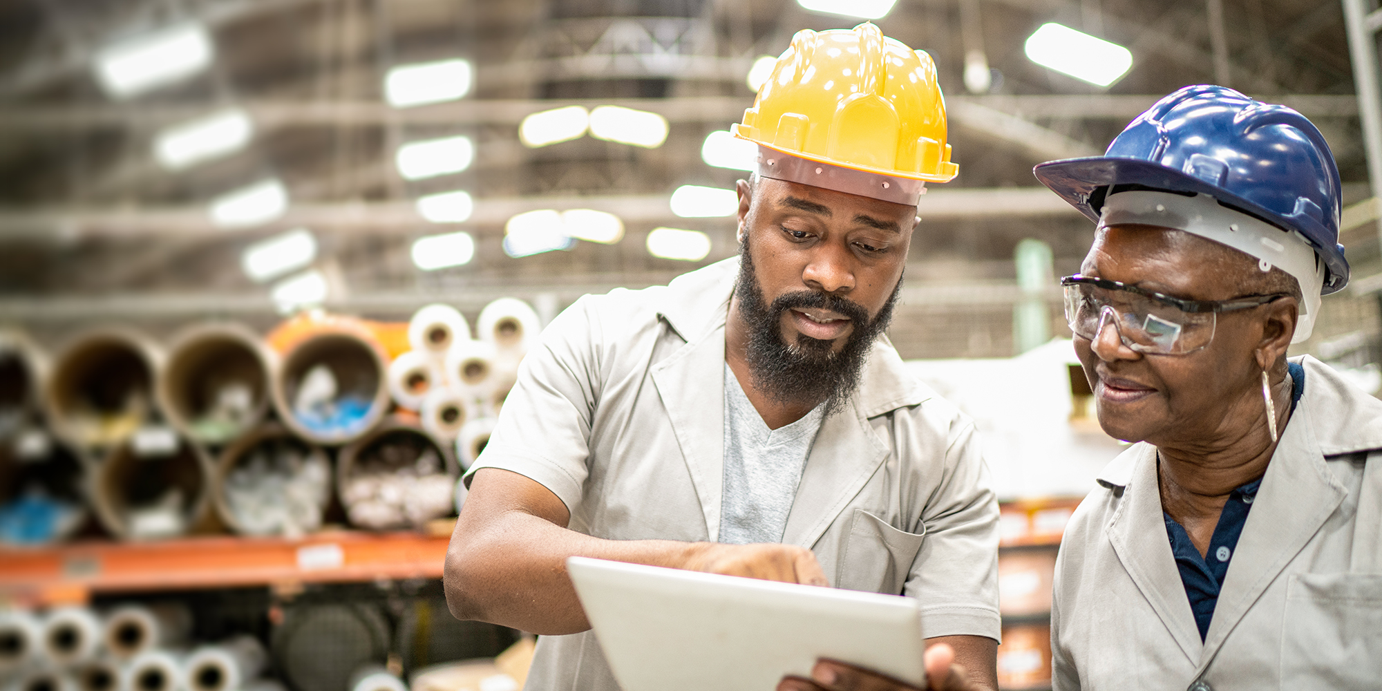 Two workers at a factory, looking at a device
