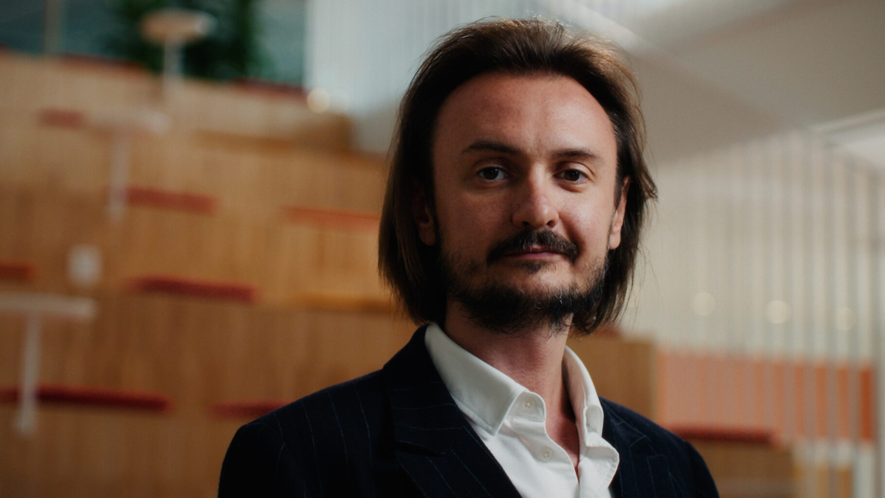 Person i kostym står framför en trätrappa i en ljus kontorsmiljö